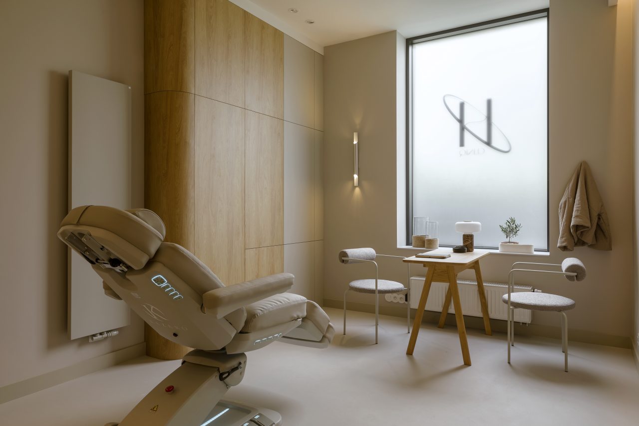 Gabinet z fotelem zabiegowym, stolikiem i oknem z logo kliniki