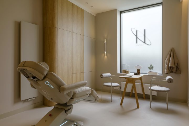 Gabinet z fotelem zabiegowym, stolikiem i oknem z logo kliniki